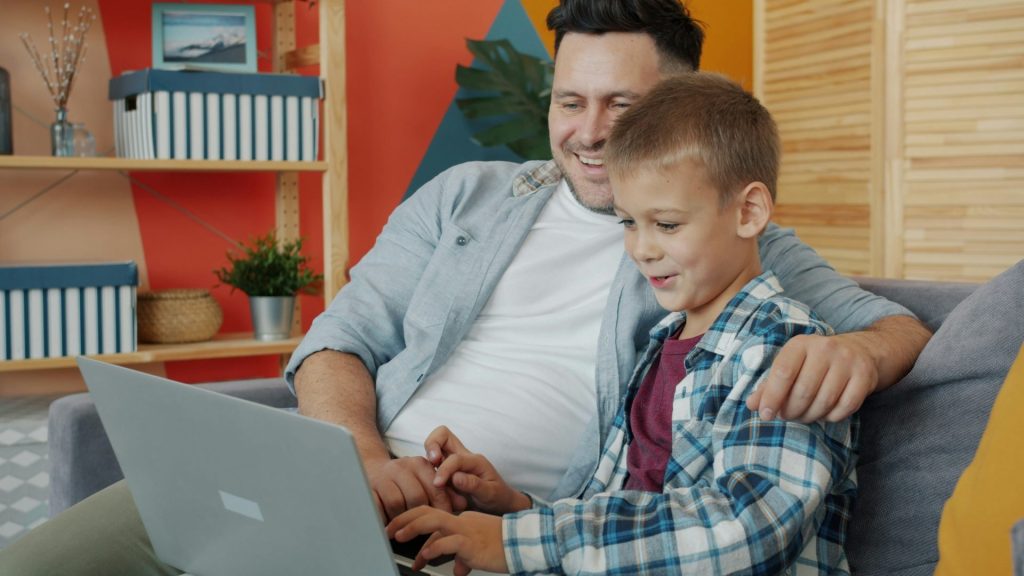 Vater und Sohn schauen gemeinsam auf einen Laptop.